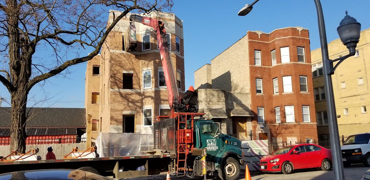 A masonry crew working from a lift on a building facade in North Lawndale